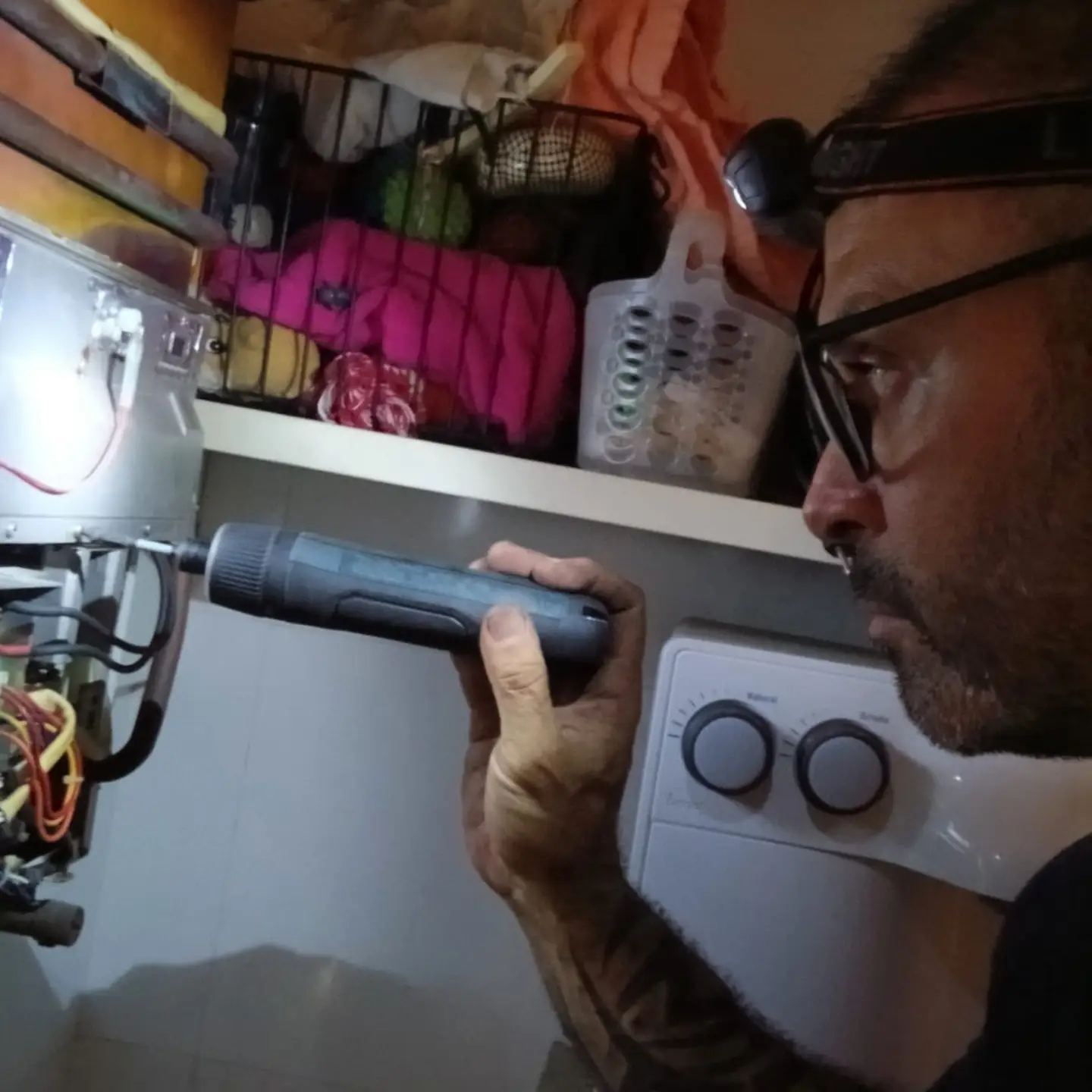 Técnico da Gás Fixe fazendo diagnóstico técnico com lanterna de cabeça em manutenção de aquecedor a gás